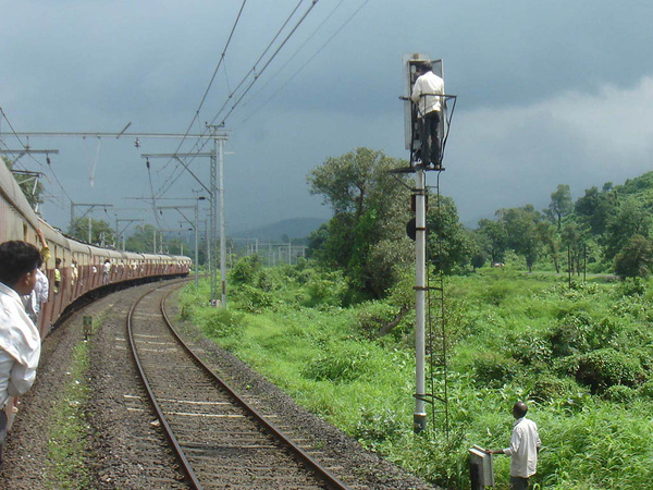 Worker atop signal as we proceed to KJT amidst dark clouds