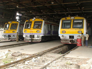 A wide angle shot of workers inspecting/repairing/working on two Mrvc and a 9xx series Ac - Dc Emu at Bct workshop. (Arzan Kotva