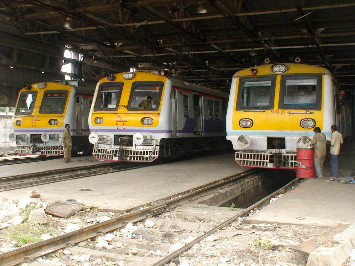 A wide angle shot of workers inspecting/repairing/working on two Mrvc and a 9xx series Ac - Dc Emu at Bct workshop. (Arzan Kotva