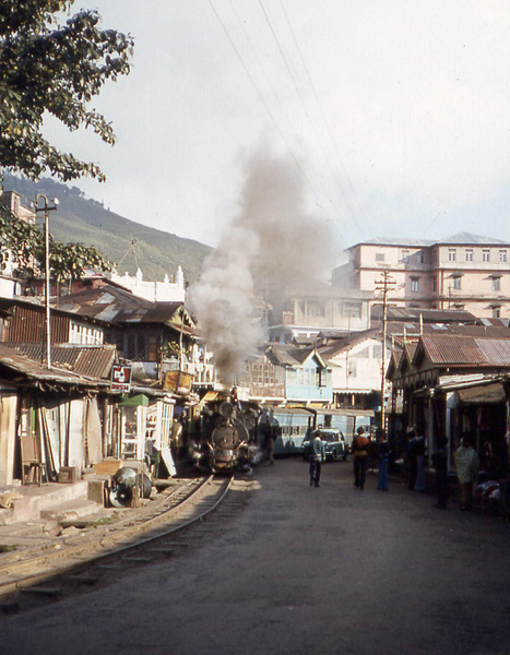 Pedestrians and road traffic vie for space with the DHR train in the narrow Kurseong Bazaar streets - Mick Pope(Jan. 9, 1980)